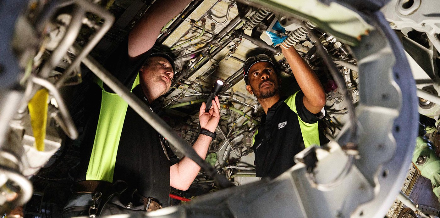 Two maintenance technicians working inside an opened aircraft engine nacelle