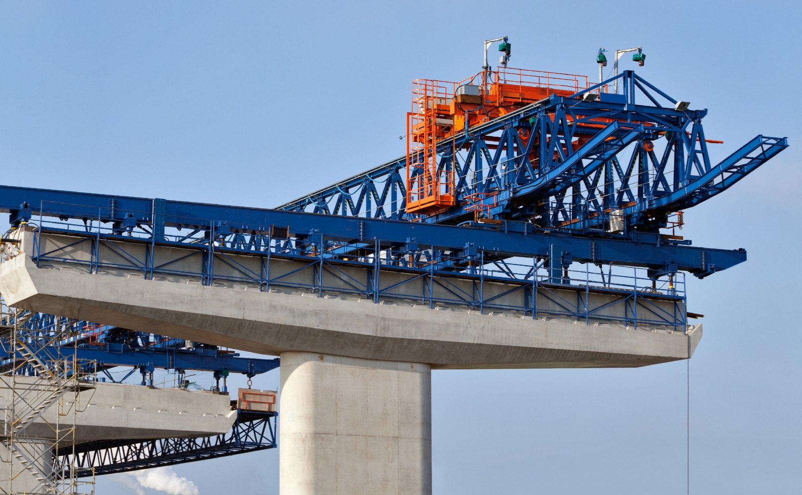 A concrete bridge deck under construction with steel launching gantries in place